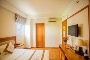 ein Schlafzimmer mit einem Bett und einem TV an der Wand in der Unterkunft Dendro Hotel in Nha Trang