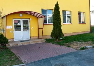 una casa gialla con una porta bianca e un albero di Apartmán Esser 2 a Milovice