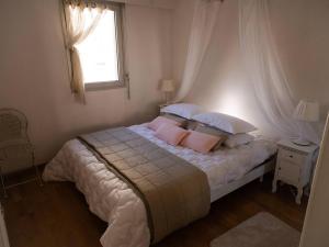a bedroom with a bed with pink pillows and a window at Les pieds dans l'eau accès direct à la plage ! in Granville