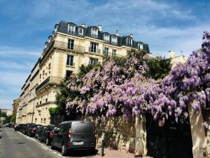 um edifício com flores roxas ao lado de uma rua em La Suite 19 em Saint-Mandé