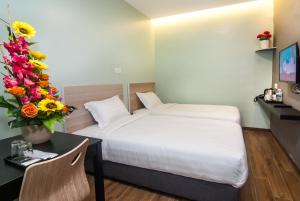 ジョホールバルにあるGOOD 9 HOTEL - Bukit Dahliaのベッド1台、デスク(花付)が備わる客室です。