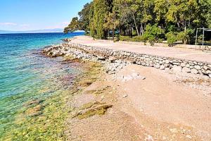 a beach with a rock wall next to the water at Apartman Helen in Malinska