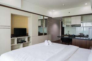 a bedroom with a large white bed and a kitchen at City View Studio Apartment at Tamansari La Grande By Travelio in Bandung