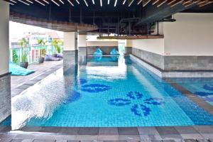 a swimming pool with blue water in a building at City View Studio Apartment at Tamansari La Grande By Travelio in Bandung