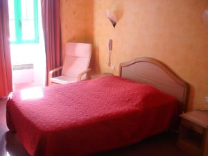 a bedroom with a red bed and a chair at Les Voyageurs in Sizun