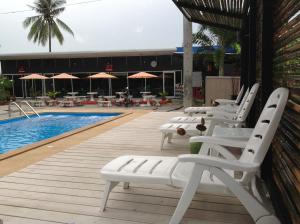 a row of white lounge chairs next to a swimming pool at Nest Boutique Resort in Lat Krabang