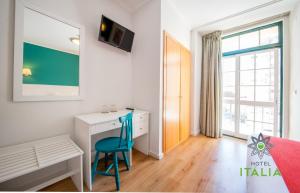 ein Schlafzimmer mit einem Schreibtisch und einem blauen Stuhl in der Unterkunft Hotel Italia in Lissabon