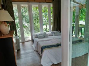 a bedroom with two beds in a room with windows at Baan Pong Tara in Suan Phung