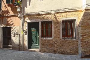 an old brick building with a green door and windows at Palazzetto Canossa in Venice
