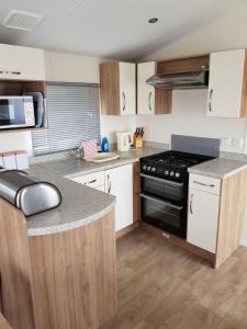 a kitchen with white cabinets and a black stove top oven at Caravan Willerby Rio in Looe