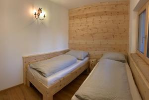 two beds in a room with wooden walls at Villa Stiegl in Steindorf am Ossiacher See
