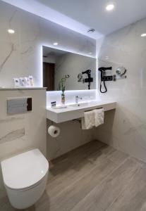 a white toilet sitting next to a sink in a bathroom at Oca Playa de Foz Hotel&Spa in Foz