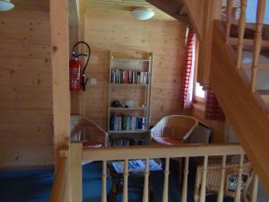 eine Treppe in einem Blockhaus mit Stühlen und einem Bücherregal in der Unterkunft Chalet Suisse Bed and Breakfast in Morgins