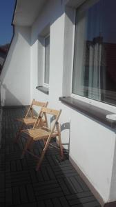 a wooden chair sitting on a balcony next to a window at Apartamenty sopot-topos in Sopot