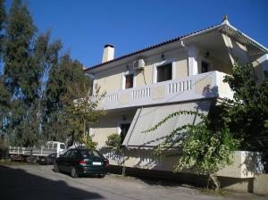 a white house with a car parked in front of it at artística in Ermioni