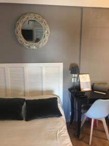 a bedroom with a bed with a desk and a mirror at Hôtel Le Mistral in Marseille