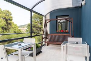 a balcony with two tables and chairs and a blue wall at CHROMA Lodge Pikermi in Pikérmion