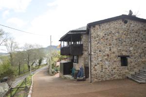 un edificio de piedra con un balcón en un lateral. en O Palleiro do Pe do Forno, en Orellán