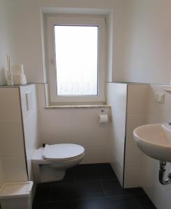 ein Bad mit einem WC, einem Waschbecken und einem Fenster in der Unterkunft Schicke Komfortwohnung zum Wohlfühlen in Merchweiler