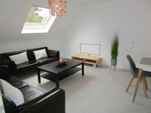 - un salon avec un canapé noir et une table dans l'établissement Schicke Komfortwohnung zum Wohlfühlen, à Merchweiler