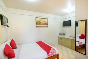 1 dormitorio con cama con almohadas rojas y espejo en Conrado's Apartelle en Manila