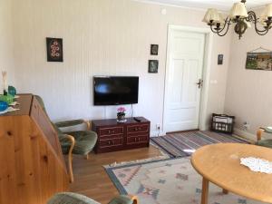 a living room with a flat screen tv and a table at Holms Heagård in Halmstad