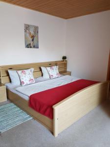 a bedroom with a large wooden bed with a red blanket at Röhrshof in Bispingen