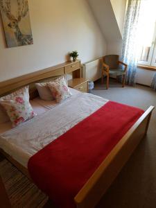 a bedroom with a large bed with a red blanket at Röhrshof in Bispingen