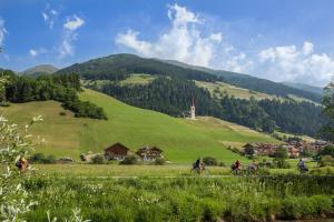 um grupo de pessoas a andar de bicicleta numa colina verde em Parggenhof em San Candido