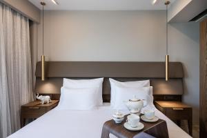 a bedroom with a large bed with white sheets and teaisers at Porto Platanias Beach Luxury Selection - Adults Only in Plataniás