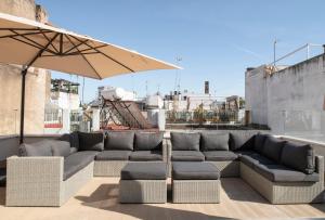 a patio with a couch and an umbrella at Hommyhome Arenal Luxury in Seville