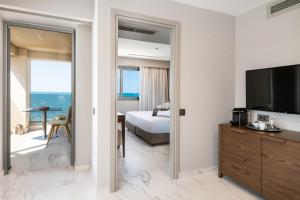 a bedroom with a bed and a television in a room at Porto Platanias Beach Luxury Selection - Adults Only in Plataniás