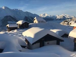 ein schneebedecktes Dorf mit Bergen im Hintergrund in der Unterkunft Hotel Alpfrieden in Bettmeralp