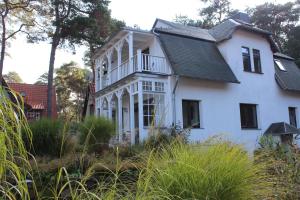 a white house with a balcony on top of it at Villa Waldheim - WG 3 in Boltenhagen