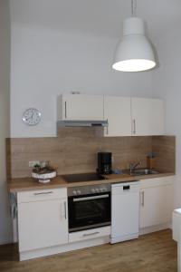 a kitchen with white cabinets and a black oven at Villa Waldheim - WG 3 in Boltenhagen