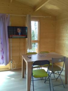 ミコワイキにあるKameralne domki w Mikolajkachのテーブル、椅子、テレビが備わる客室です。
