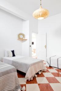 a white room with two beds and a checkered floor at Surf And Soul Morocco in Oualidia
