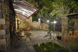 a stone patio with a table and an umbrella at Santa Marina Guesthouse in Kato Loutraki