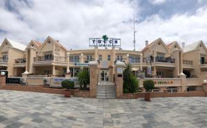 un gran edificio con un patio delante de él en Yucca Park ApartHotel en Adeje