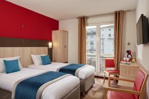 two beds in a hotel room with a red wall at Hôtel Roissy in Lourdes