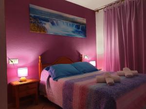 a bedroom with a bed with purple walls and two lamps at Pension los Verdiales in La Herradura