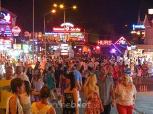 een menigte mensen die 's nachts over straat lopen bij Hotel NilSu in Oludeniz