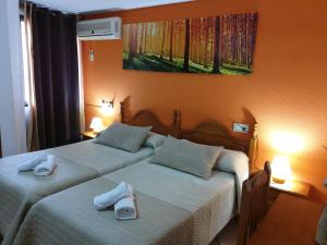 two beds in a hotel room with towels on them at Pension los Verdiales in La Herradura