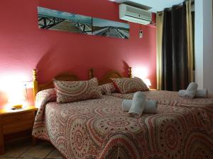 a bedroom with a bed with a red wall at Pension los Verdiales in La Herradura