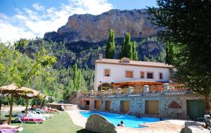 una casa con piscina frente a una montaña en Hospedería Río Zumeta Spa en Santiago de la Espada