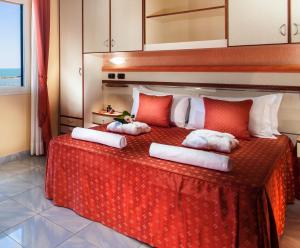 a bedroom with a bed with red and white pillows at Hotel Excelsior in Cesenatico