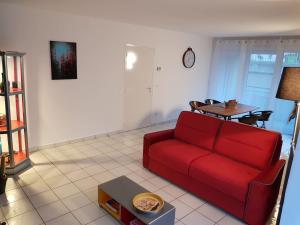 a living room with a red couch and a table at A 100 m de la mer et du port ! Parking privatif ! in Fécamp