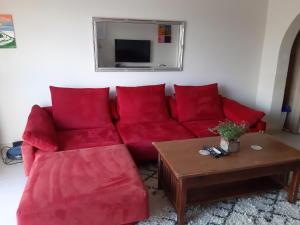 um sofá vermelho numa sala de estar com uma mesa em Penthouse view em Qbajjar