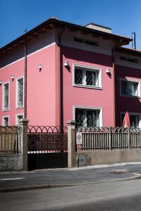 un bâtiment rose avec une clôture devant lui dans l'établissement Villa Vietnamonamour, à Milan