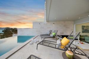 a patio with chairs and a swimming pool at BEACHSIDE VILLA plus APARTMENT - AVA - at SUNSET COVE LUXURY VILLAS, 5 BED 5 BATH, Amazing SEA and MOUNTAIN VIEWS, only 100m walk to Swimming Beach in Bang Rak Beach